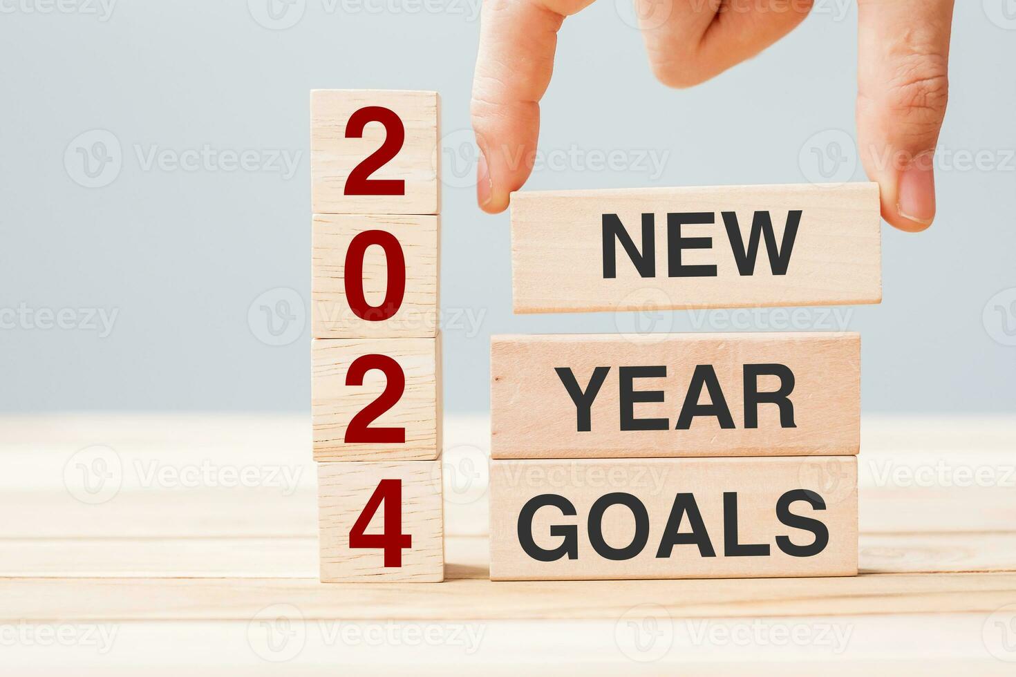 hand holding wooden block with text 2024 NEW YEAR NEW GOALS on table background. Resolution, strategy, solution, business and holiday concepts photo