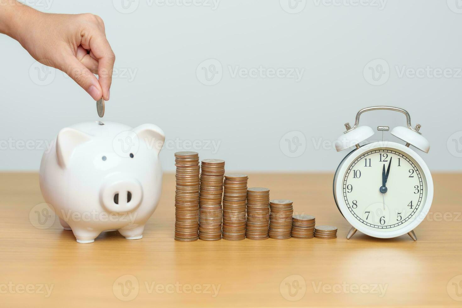Money Saving for Future Plan, Retirement fund, Pension, Investment, Wealth Business and Financial concepts. hand putting coin into piggy bank with clock, Counting and stack arrangement for deposit photo