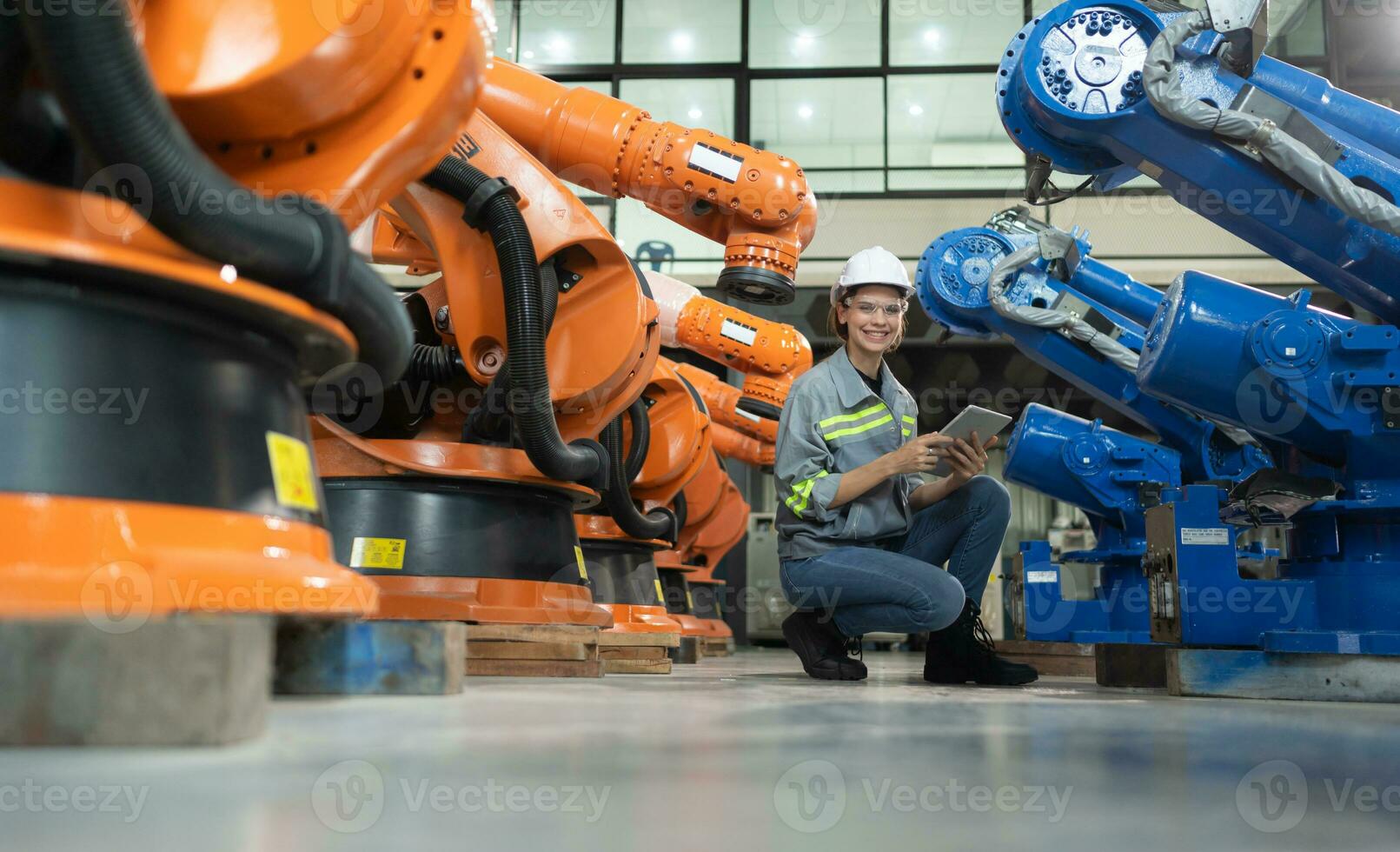 A female engineer installs a program on a robotics arm in a robot warehouse. And test the operation before sending the machine to the customer. photo
