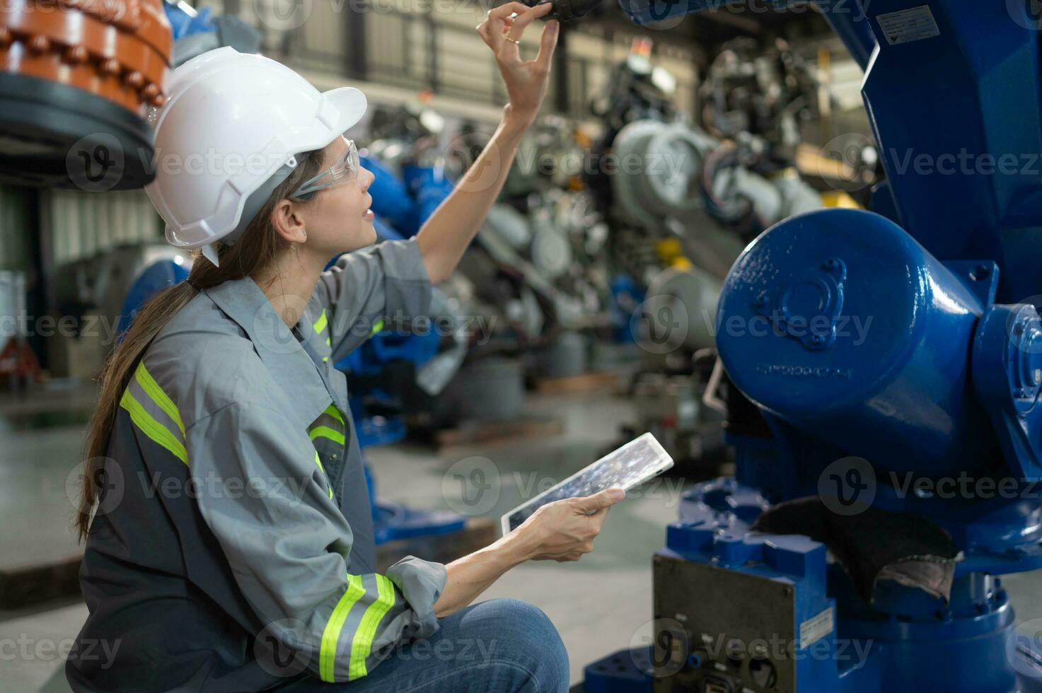 A female engineer installs a program on a robotics arm in a robot warehouse. And test the operation before sending the machine to the customer. photo