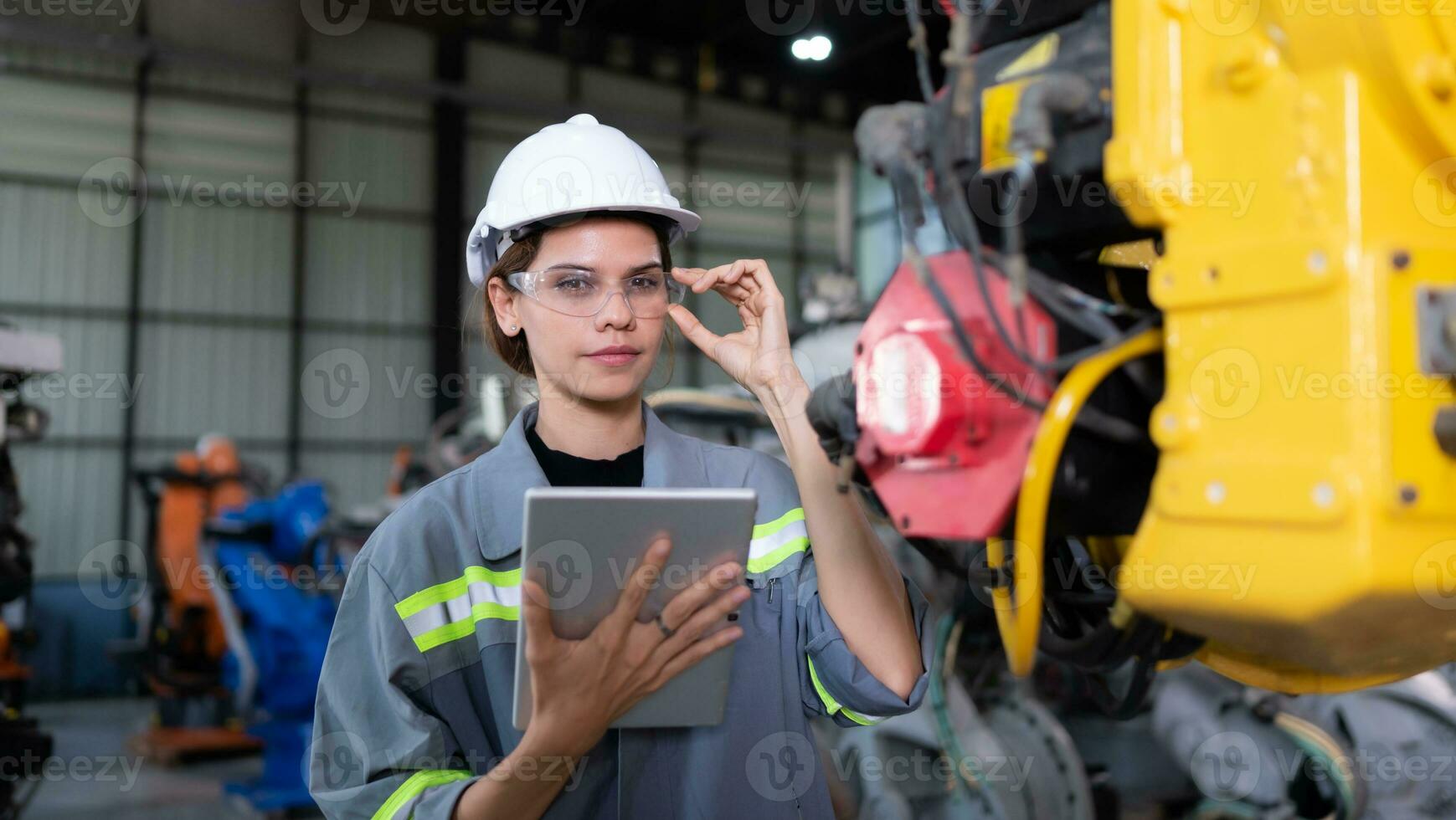 A female engineer installs a program on a robotics arm in a robot warehouse. And test the operation before sending the machine to the customer. photo