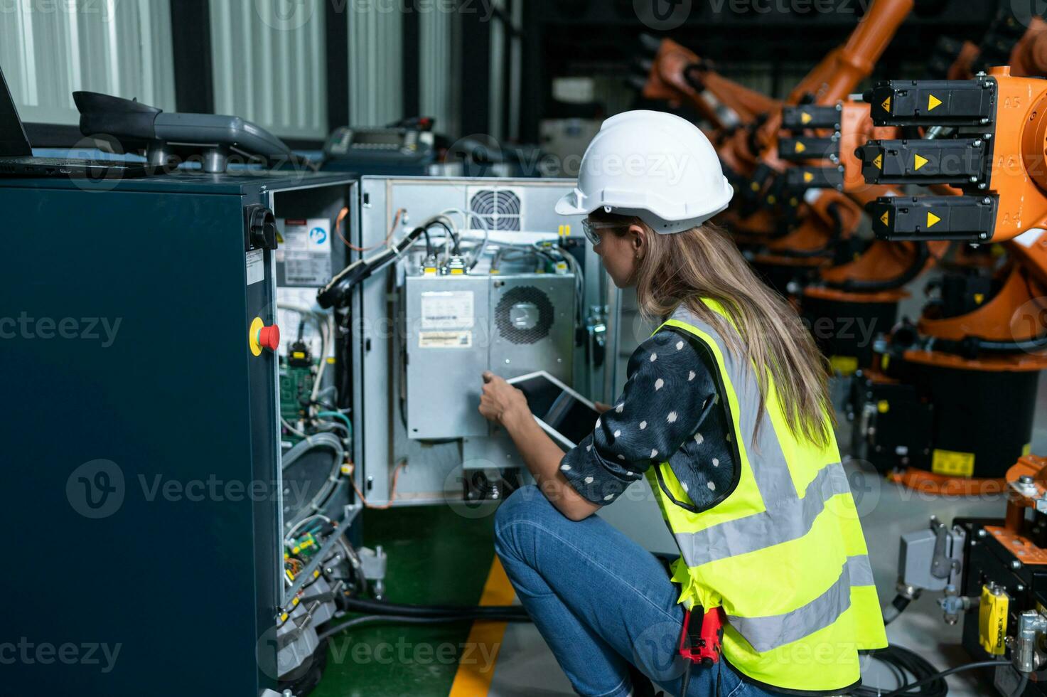 Female Technician Inspecting and repairing robotics arm in robots hangar and test the operation of the machine after being used for a while, as well as updating the software and calibration photo