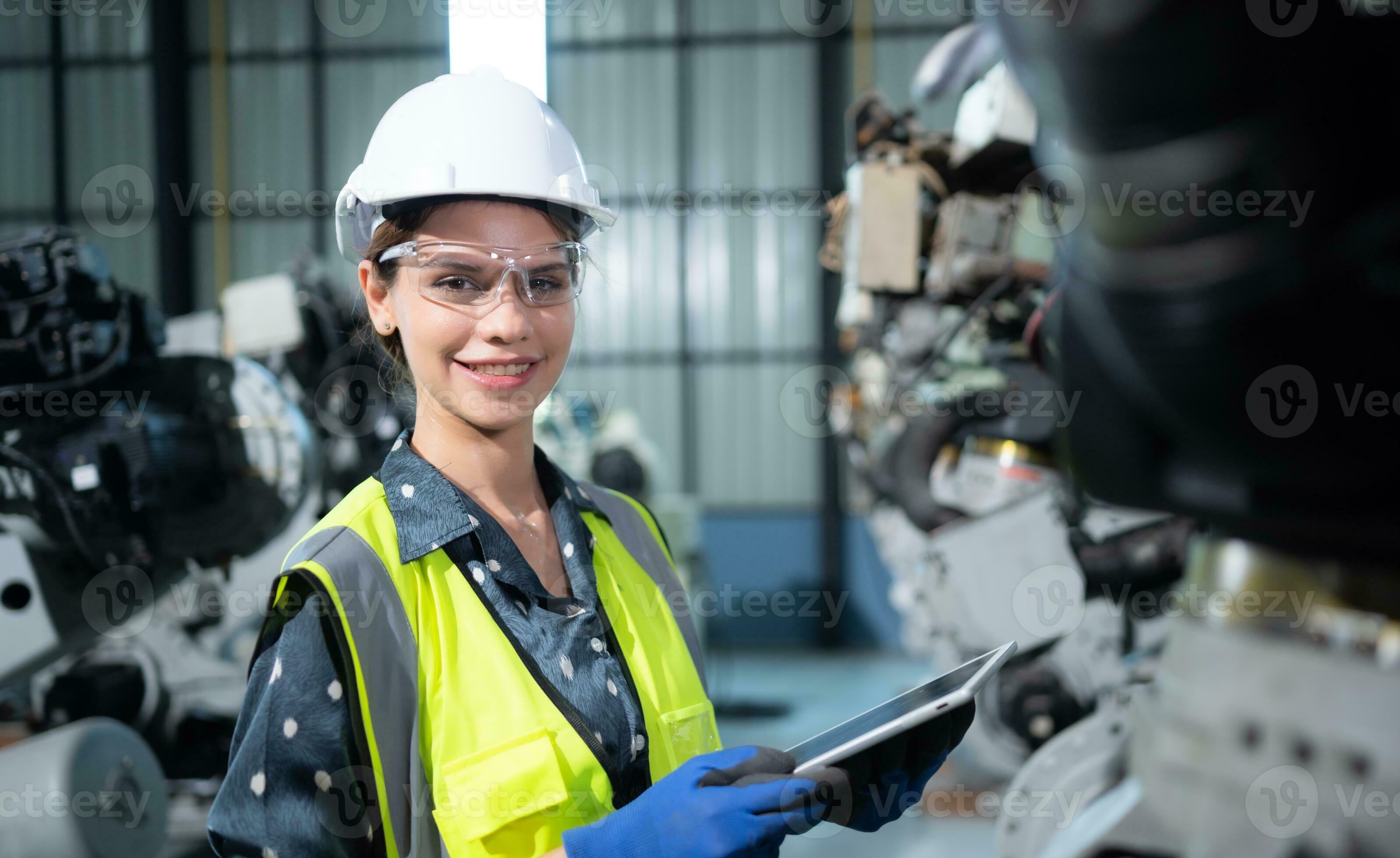 A female engineer installs a program on a robotics arm in a robot