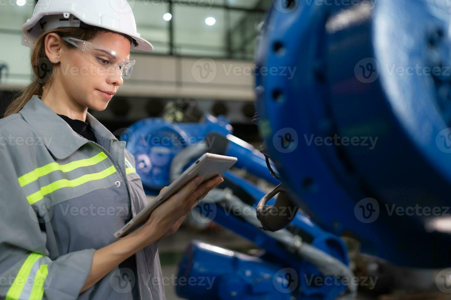 A female engineer installs a program on a robotics arm in a robot warehouse. And test the operation before sending the machine to the customer. photo