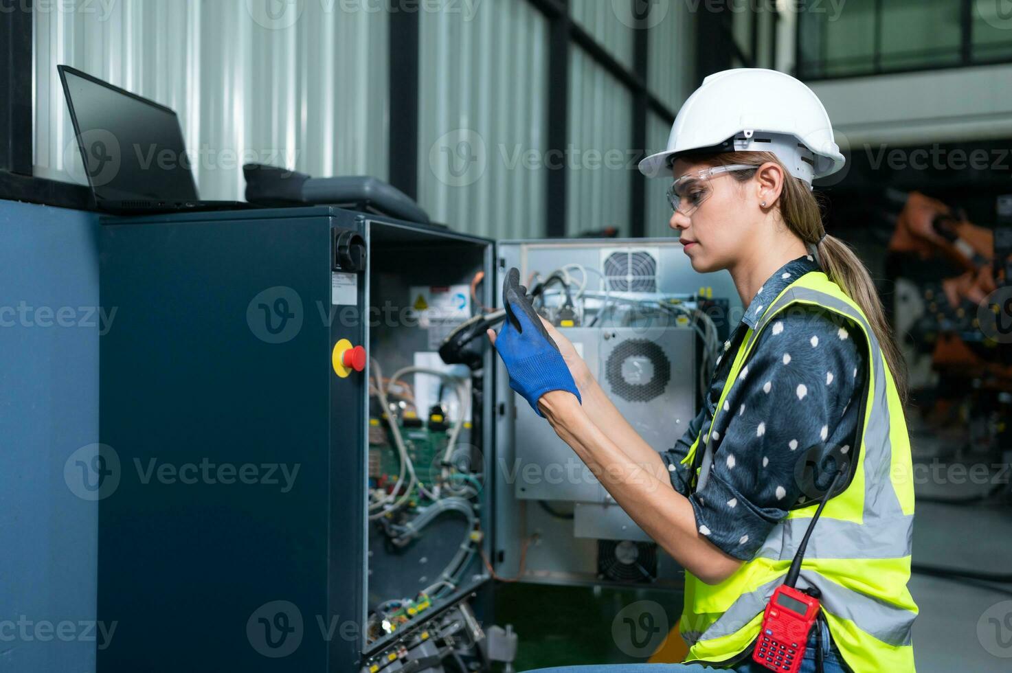 Female Technician Inspecting and repairing robotics arm in robots hangar and test the operation of the machine after being used for a while, as well as updating the software and calibration photo