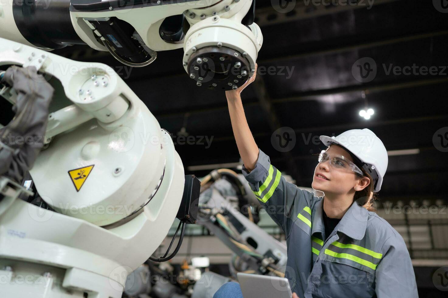 A female engineer installs a program on a robotics arm in a robot warehouse. And test the operation before sending the machine to the customer. photo