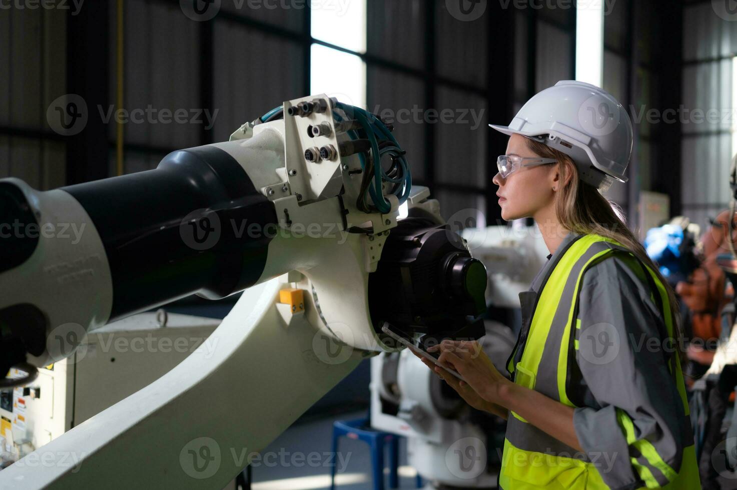 In the robots warehouse, Female engineer happily with updating software and calibrating a robotics arm. photo