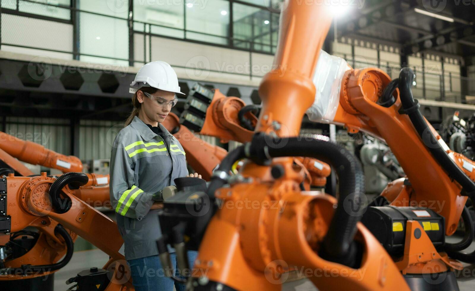After installing a program on the robotic arm, a female engineer with a robotic arm controller performs a test run. photo