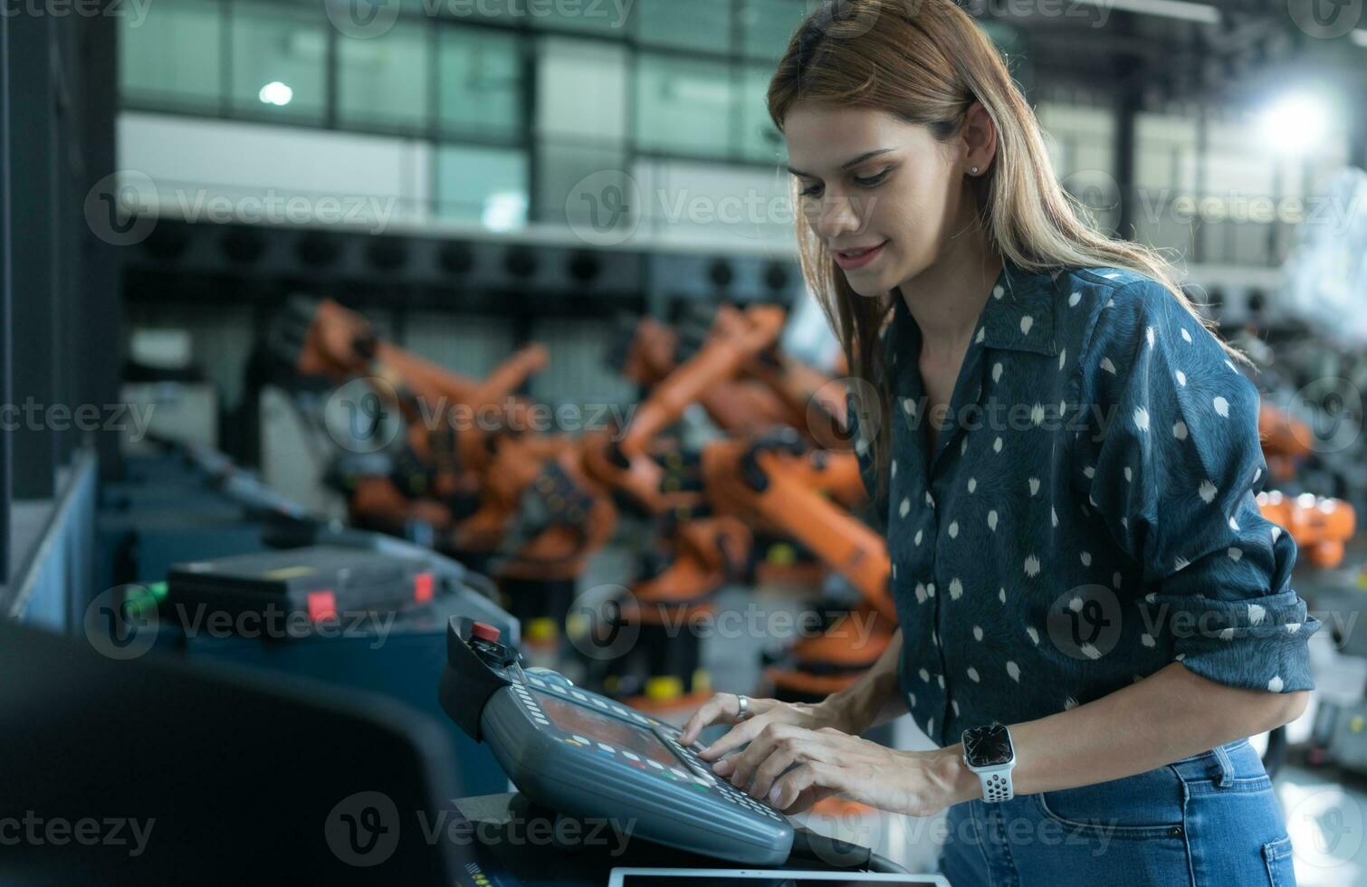A female engineer installs a program on a robotics arm in a robot warehouse. And test the operation before sending the machine to the customer. photo