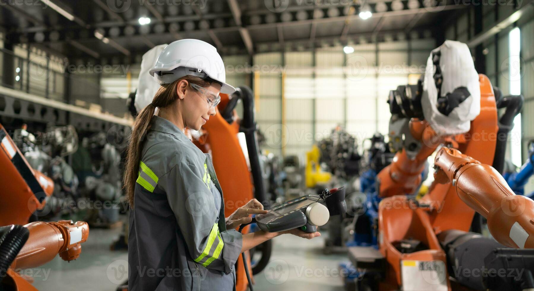 después instalando un programa en el robótico brazo, un hembra ingeniero con un robótico brazo controlador realiza un prueba correr. foto