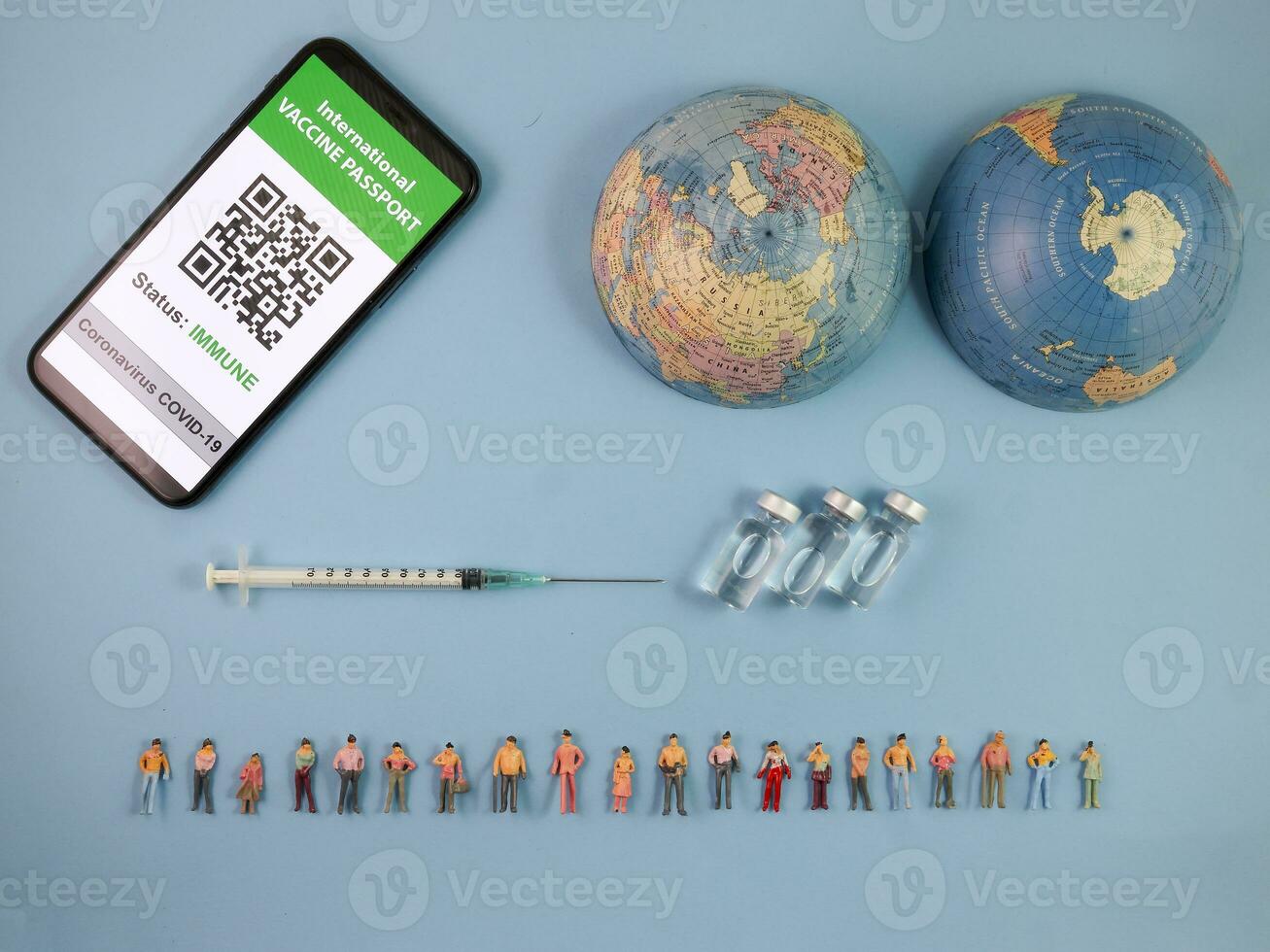 Miniature human figure figurine male female doll row vaccine passport digital paper book bottle medical injection syringe needle world map globe border copy text sign space on blue paper background photo