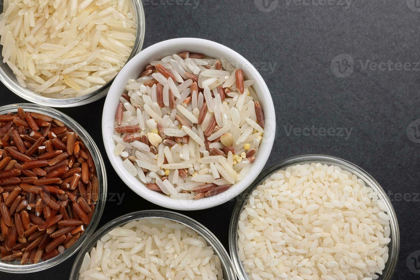 Long grain basmati medium grain jasmine short grain pilaf polau risotto brown low glycaemic index gi rice in small glass bowl on black background copy text space top flat lay view border frame photo