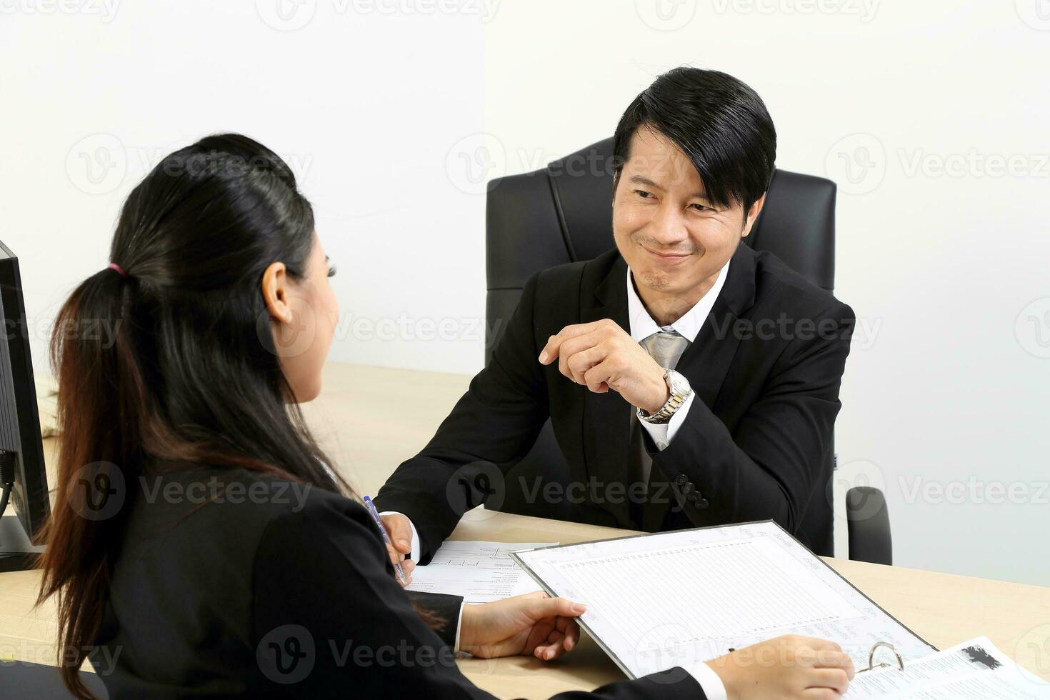 Young Asian male female wearing suit sitting at office desk thinking meeting disucsing sign document agreement photo