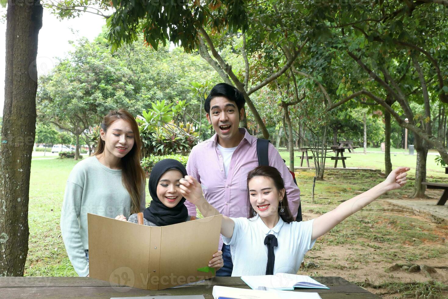 Young asian malay chinese man woman outdoor park  book file folder laptop computer phone sit stand study mingle photo