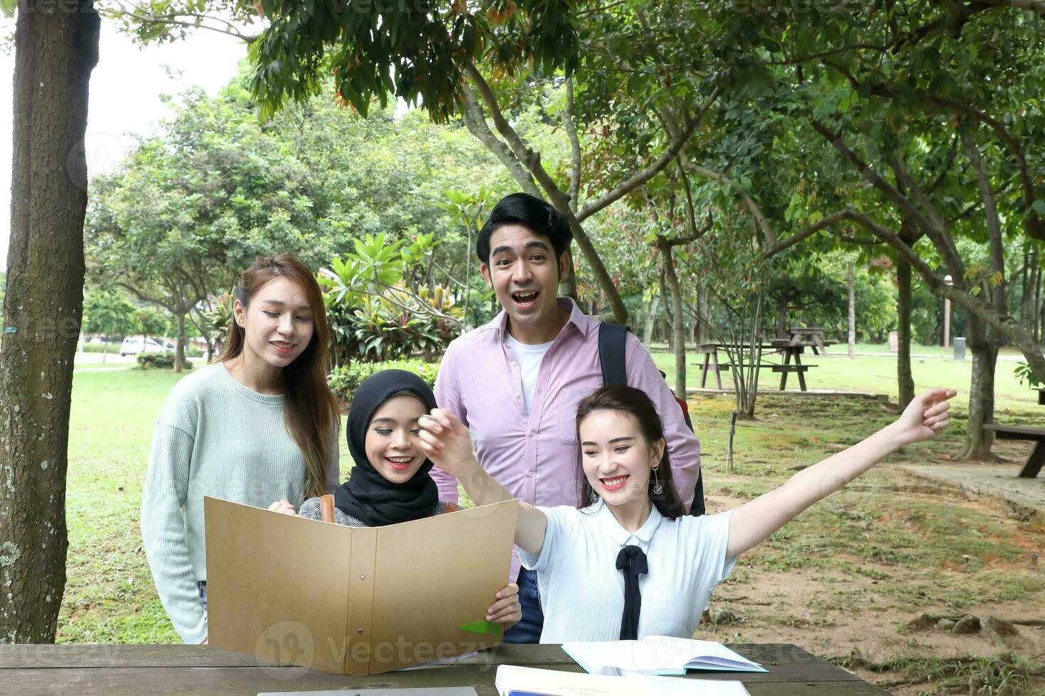 joven asiático malayo chino hombre mujer al aire libre parque libro archivo carpeta ordenador portátil computadora teléfono sentar estar estudiar mezclarse foto