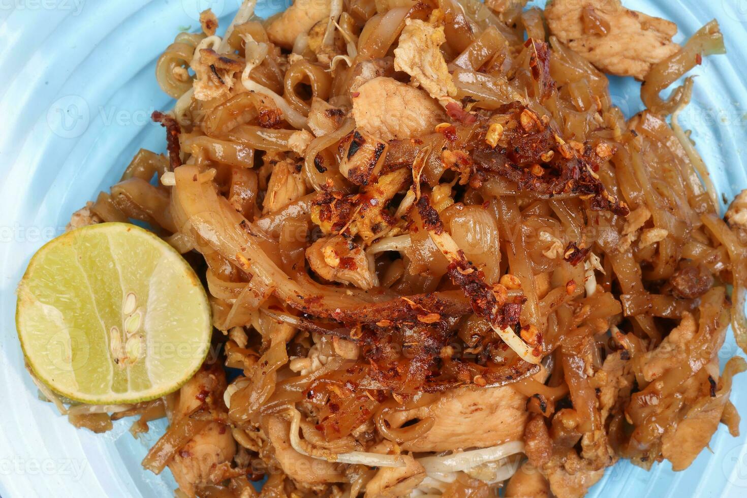 Thai style stair fried flat rice noodles pad thai on a blue glass