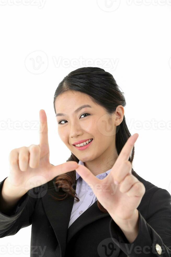 Southeast Asian young office business woman wearing suit framing face with finger smile expression look at camera on white studio background photo