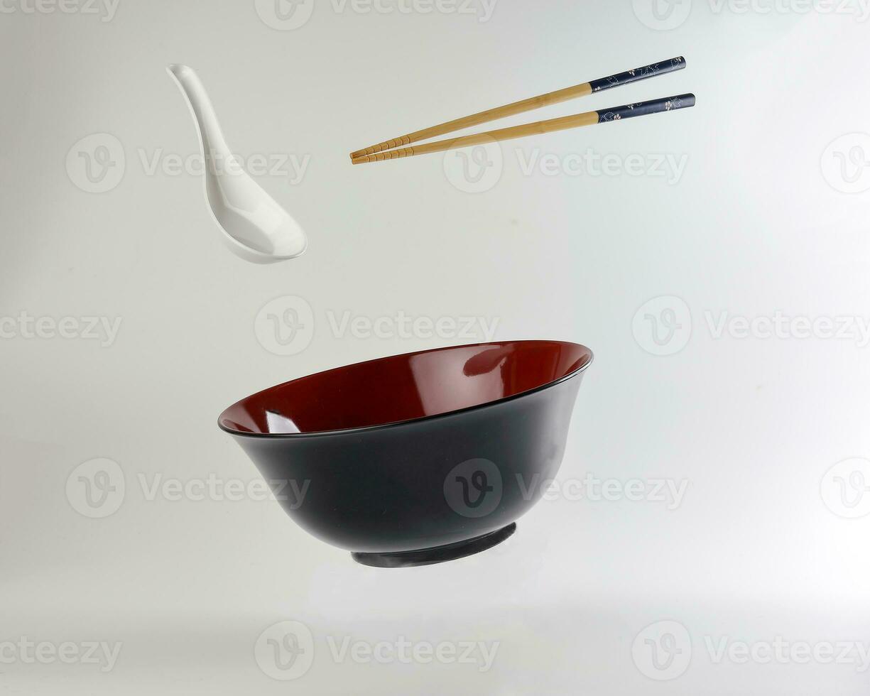Empty oriental Japanese Chinese soup bowl spoon chopstick elevated flying in air red black white photo
