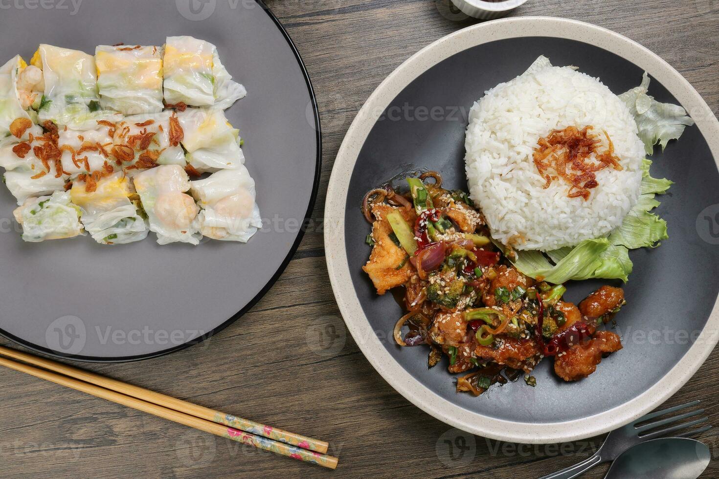 Chinese style Kung Pao Gong Bao Kung Po stair fried chicken and rice noodle roll cheung fun stuffed shrimp chicken vegetable on dark plate sauce fork spoon chopsticks on rustic dark wood table photo