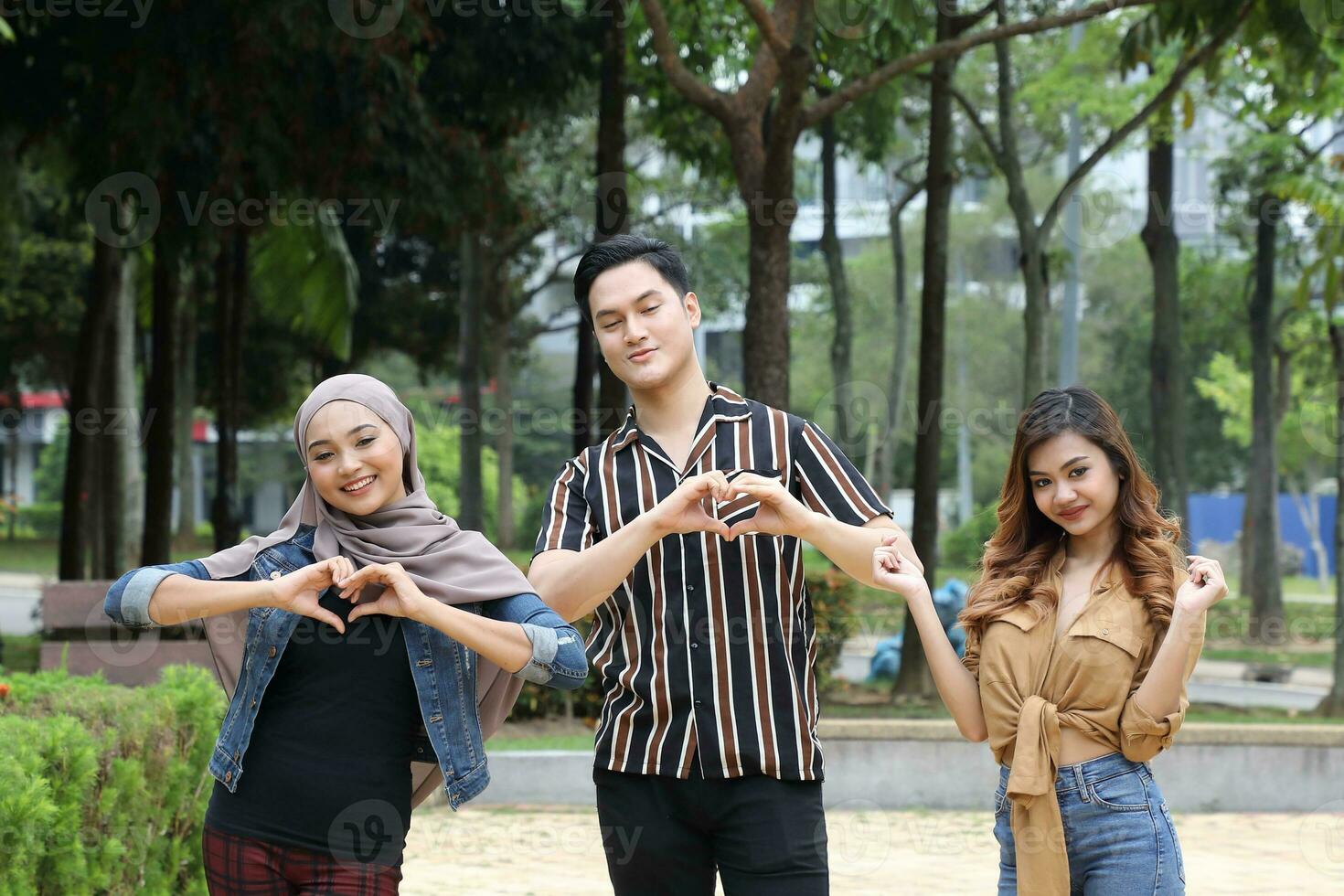 Young Asian Malay man woman outdoor green park walk talk discuss mingle sign show photo