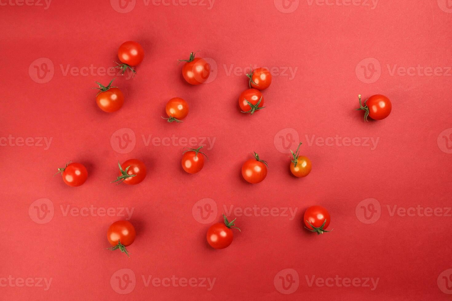 Red ripe cherry tomato with stem on red paper background copy text space photo