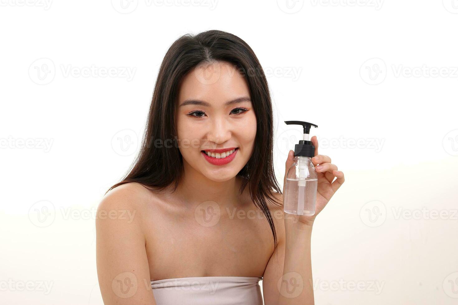 Beautiful young south east Asian woman posing holding transparent liquid hand sanitizer plastic bottle pose see offer white background smile photo