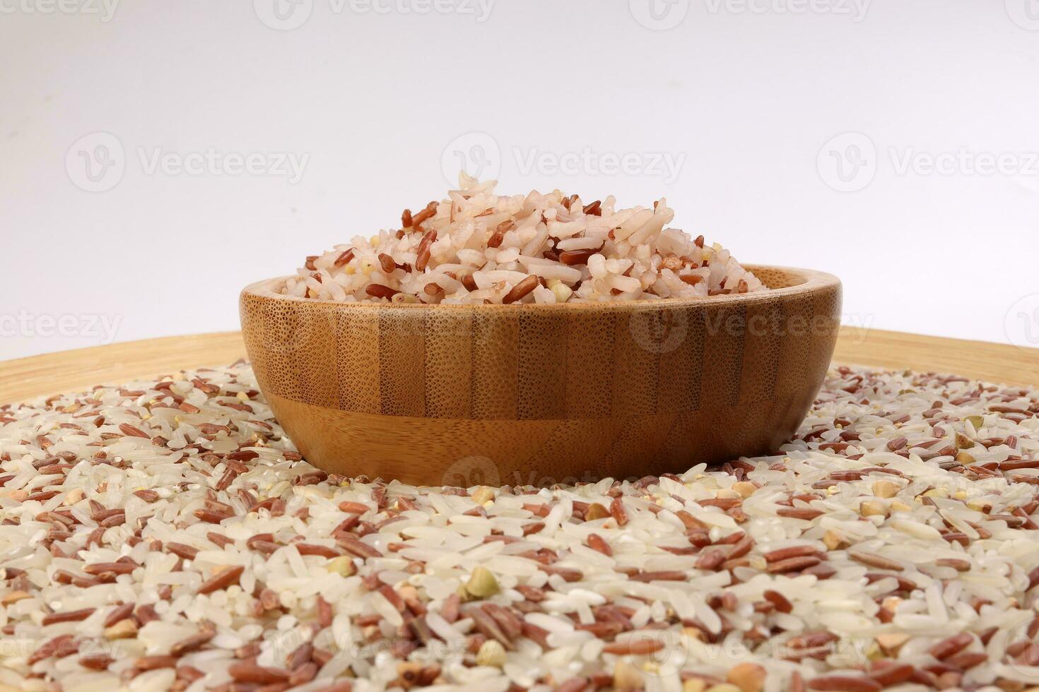 Cooked and raw mixed low glycaemic index healthy rice grain basmati millet buckwheat red rice in wooden bowl over wooden plate on white background photo