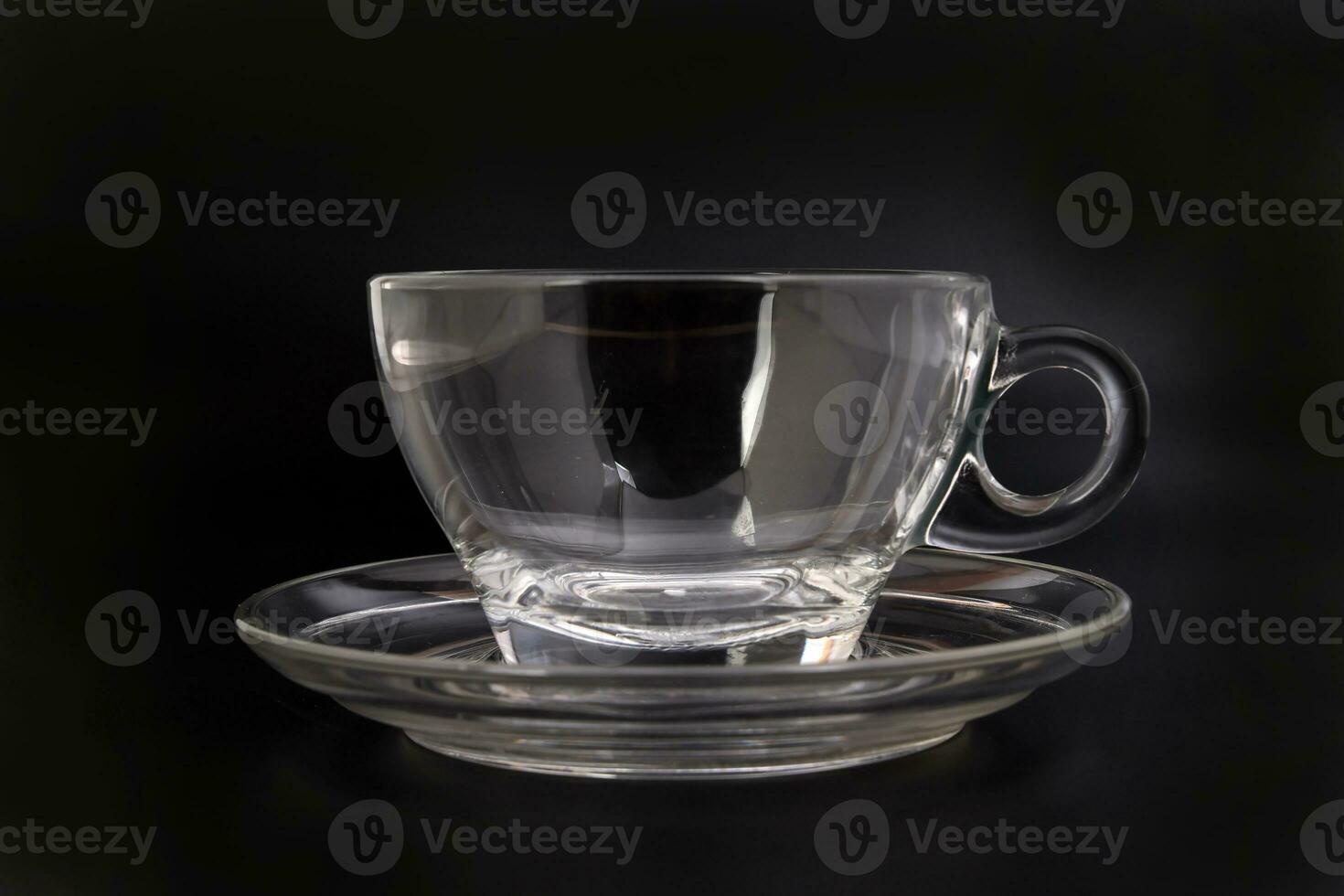 Empty transparent glass see through coffee tea cup saucer on black background photo