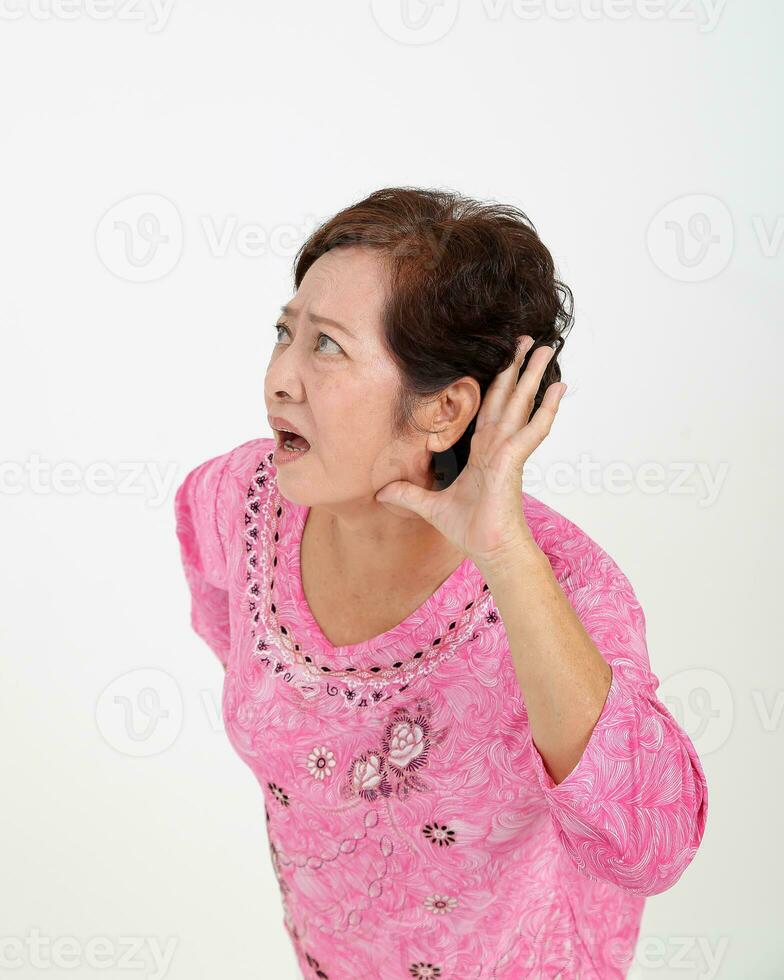 Elderly asian Chinese female on white background ease dropping hand on ear trying to listen photo