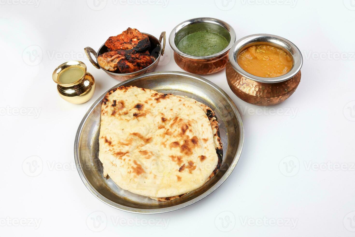 Spicy red Chicken grilled tikka tandoori nan bread green spinach curry yogurt sauce dal tomato cucumber onion salad set in metal stainless steel brass copper pot on white background photo