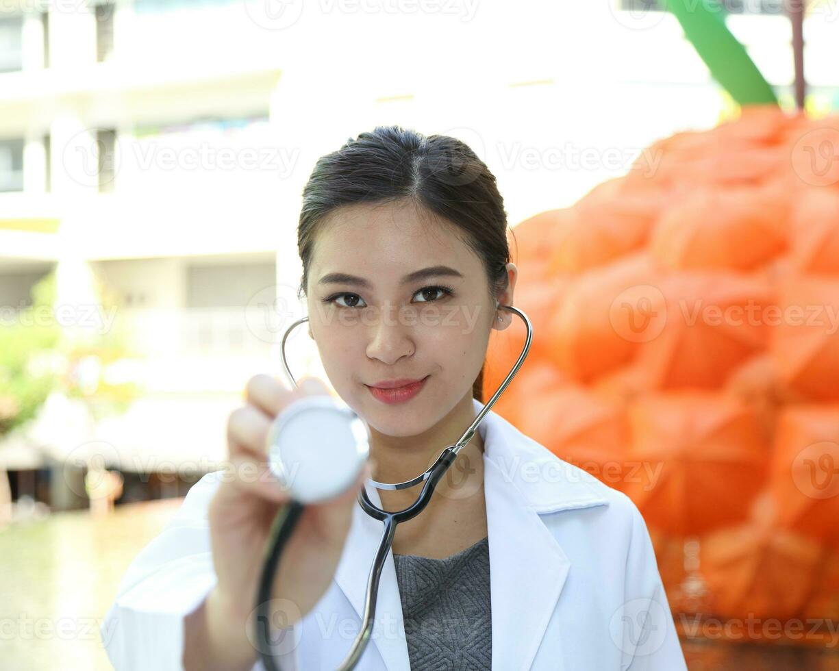 South East Asian young Malay Chinese woman medical doctor hold stethoscope to camera photo