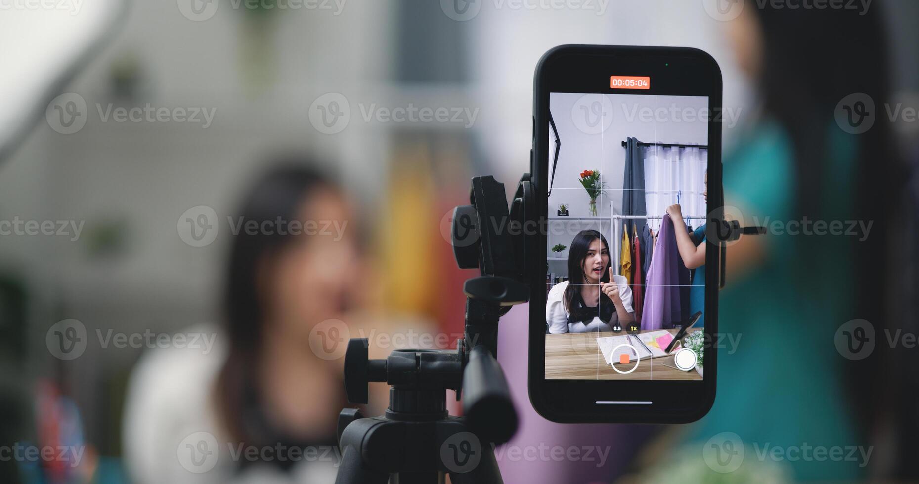 Young Asian female fashion designer using mobile phone live steaming photo