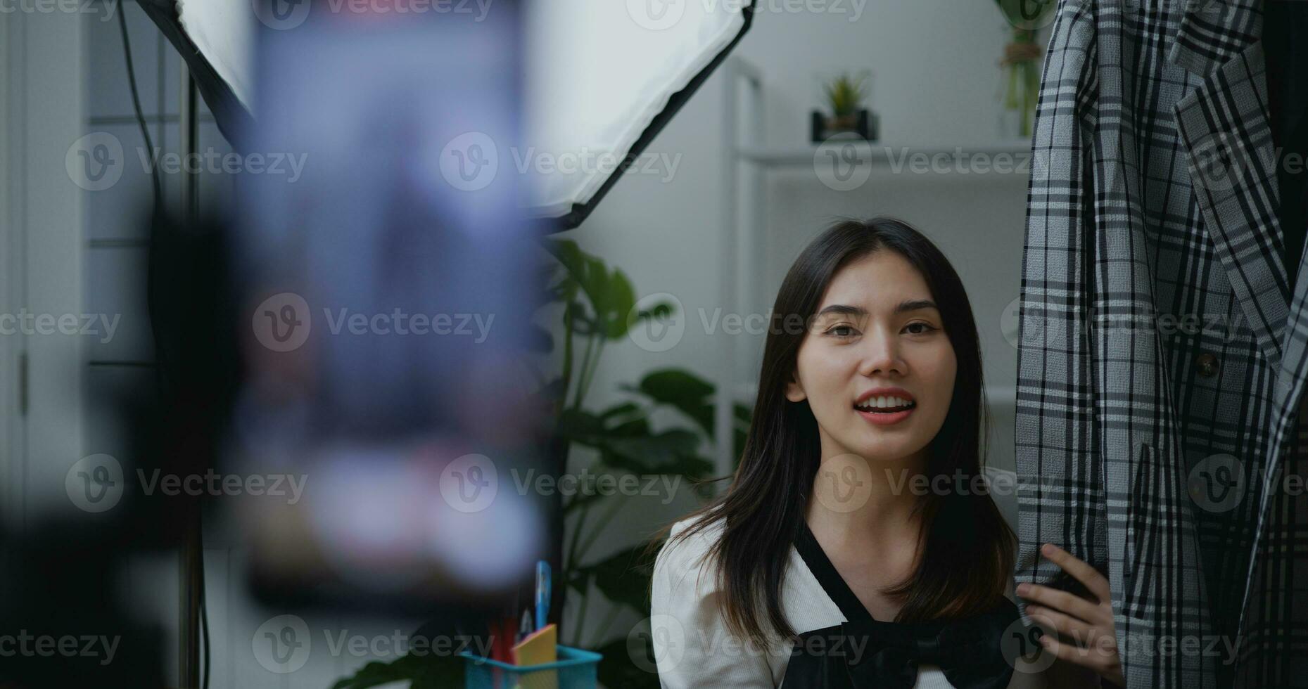 Young Asian female fashion designer using mobile phone live steaming photo