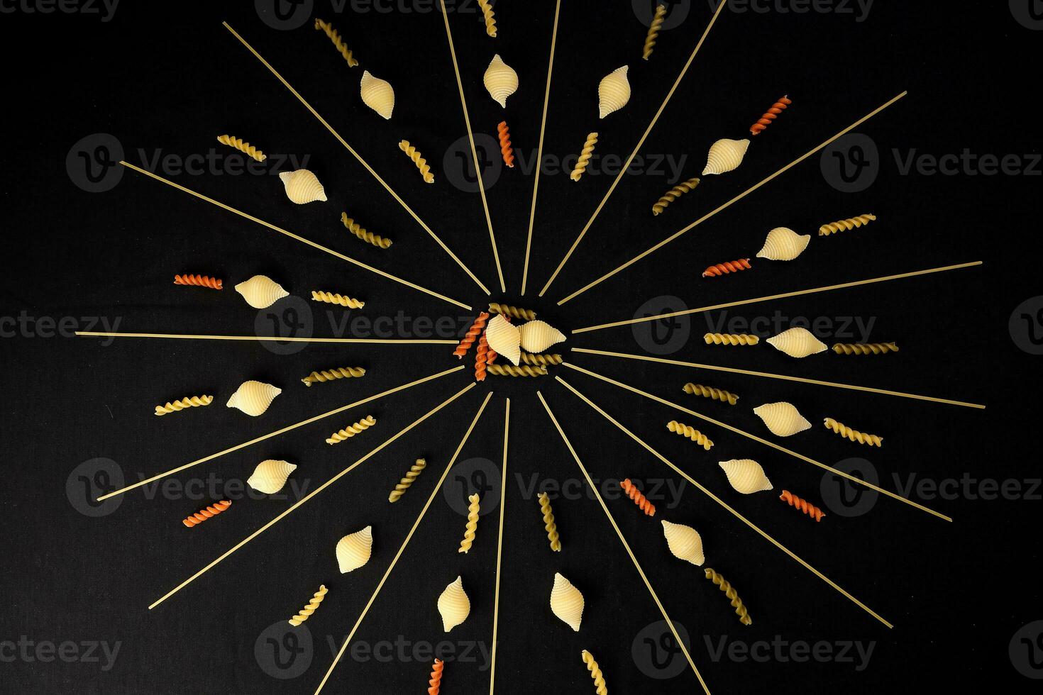 dry raw spaghetti conchiglie seashells fusilli cork screw color pasta laid on black background sunray glow pattern concept photo