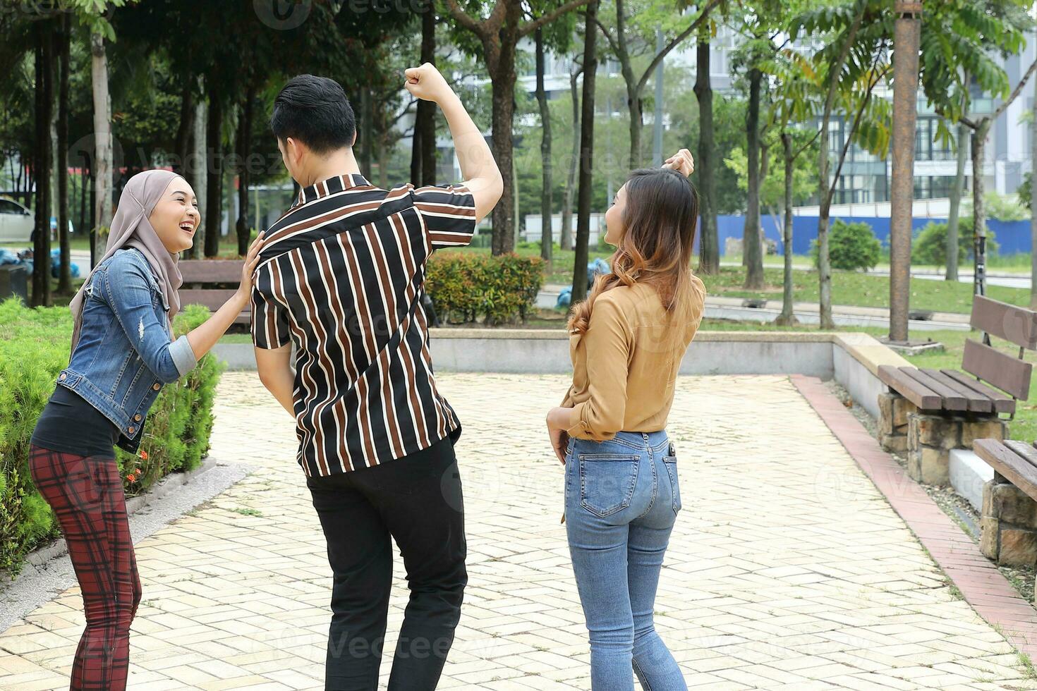 Young Asian Malay man woman outdoor green park walk talk discuss mingle sign show photo