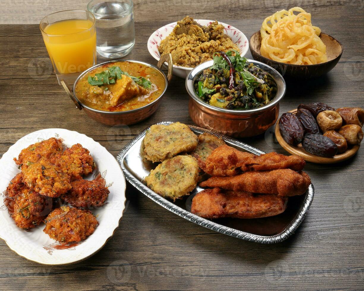 bengalí iftar Ramadán desayuno untado maduro fechas mirar furtivamente frito picante piju cebolla ajustador berenjena tanpura patata picar haleem jilapi kichuri arroz chana sola curry en rústico de madera mesa foto
