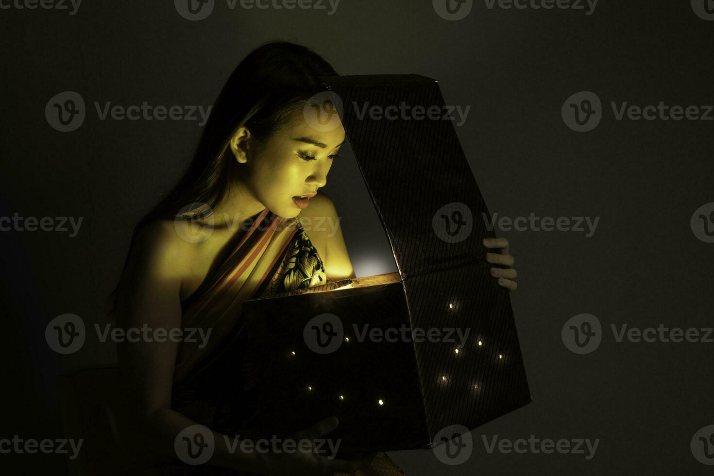 Asian woman opening mystic book box magical light dark background photo