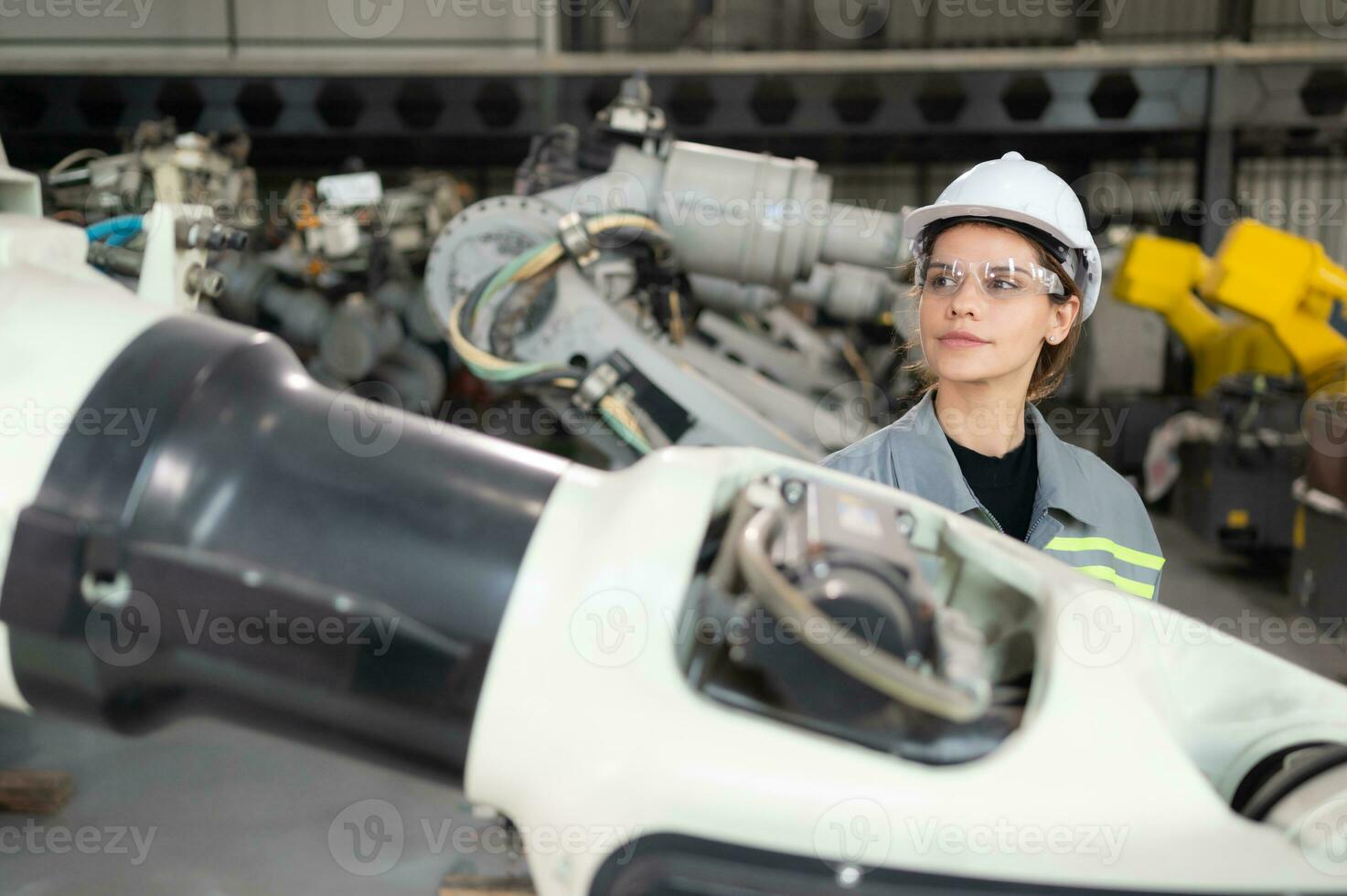 A female engineer installs a program on a robotics arm in a robot warehouse. And test the operation before sending the machine to the customer. photo