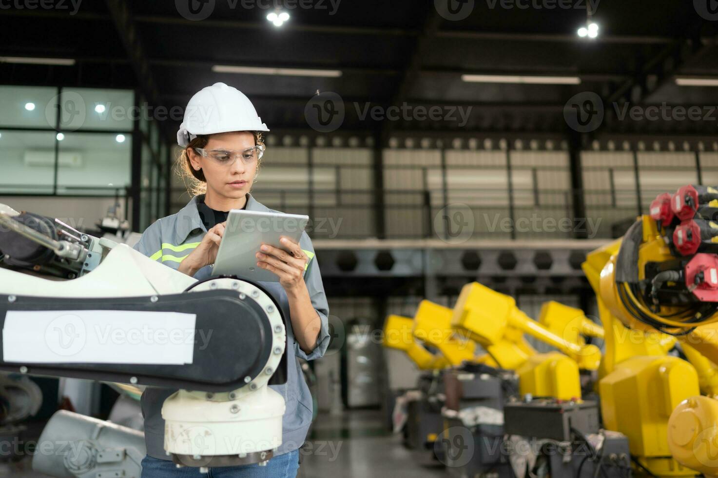 un hembra ingeniero instala un programa en un robótica brazo en un robot depósito. y prueba el operación antes de enviando el máquina a el cliente. foto