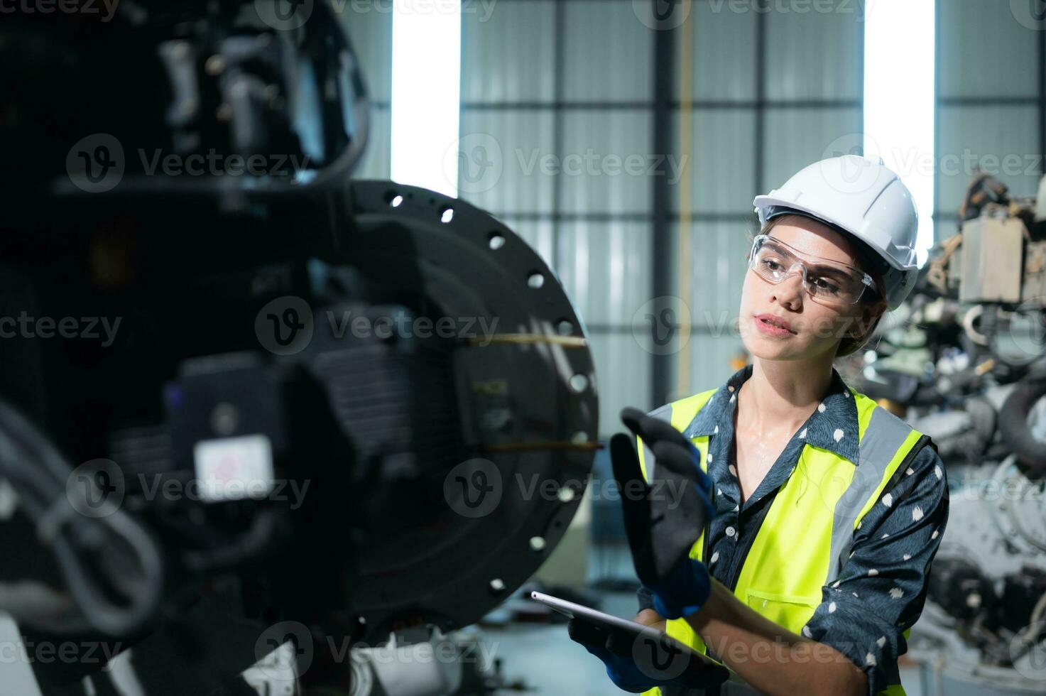 un hembra ingeniero instala un programa en un robótica brazo en un robot depósito. y prueba el operación antes de enviando el máquina a el cliente. foto