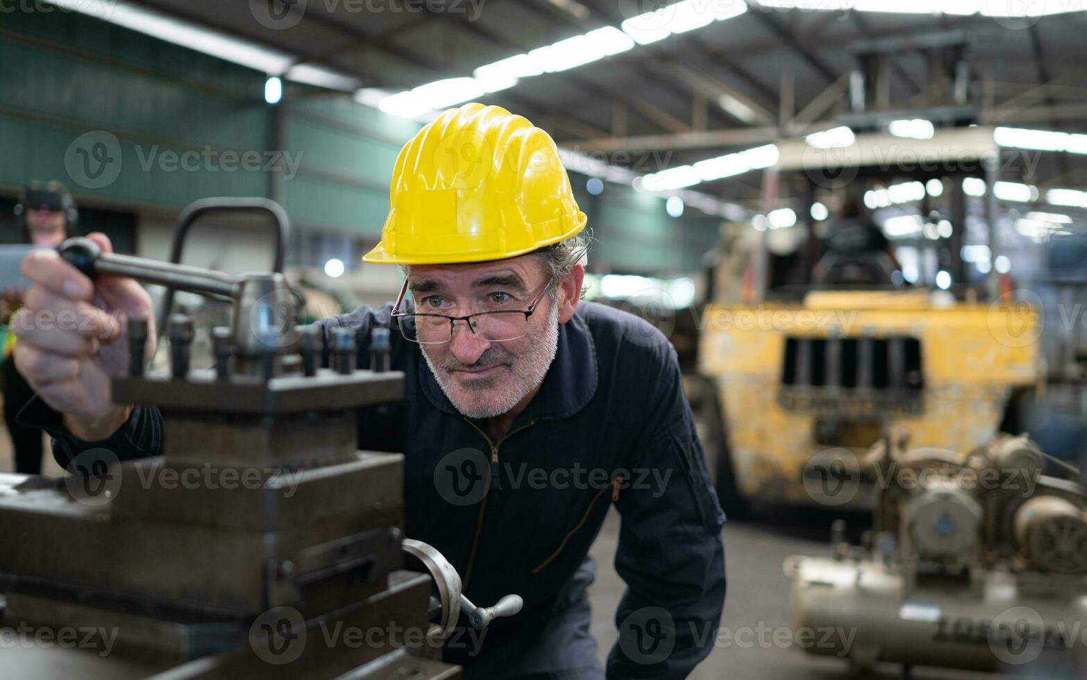 An elderly technician uses a computer to test the operation control of a steel punching machine. photo