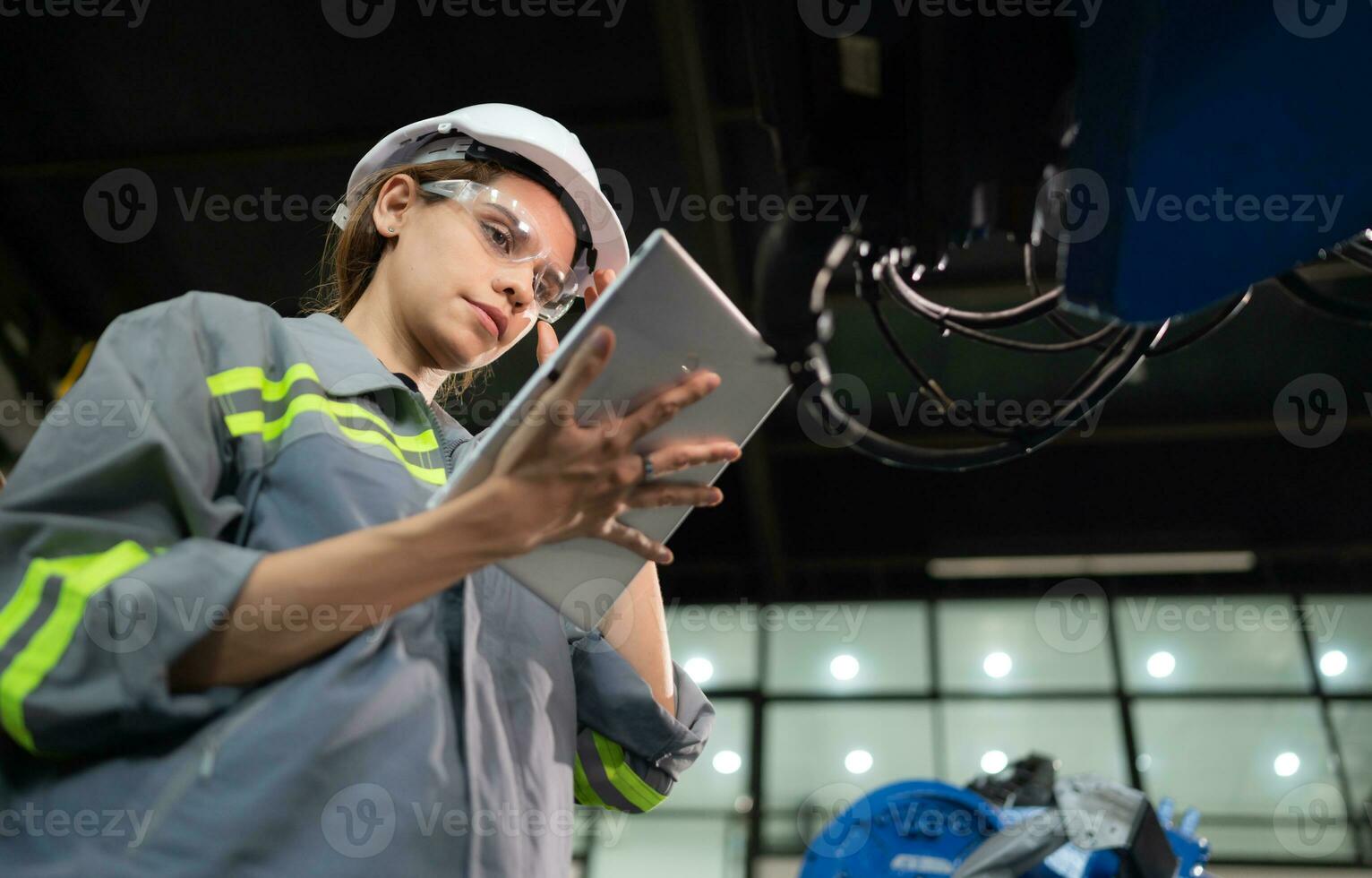 A female engineer installs a program on a robotics arm in a robot warehouse. And test the operation before sending the machine to the customer. photo