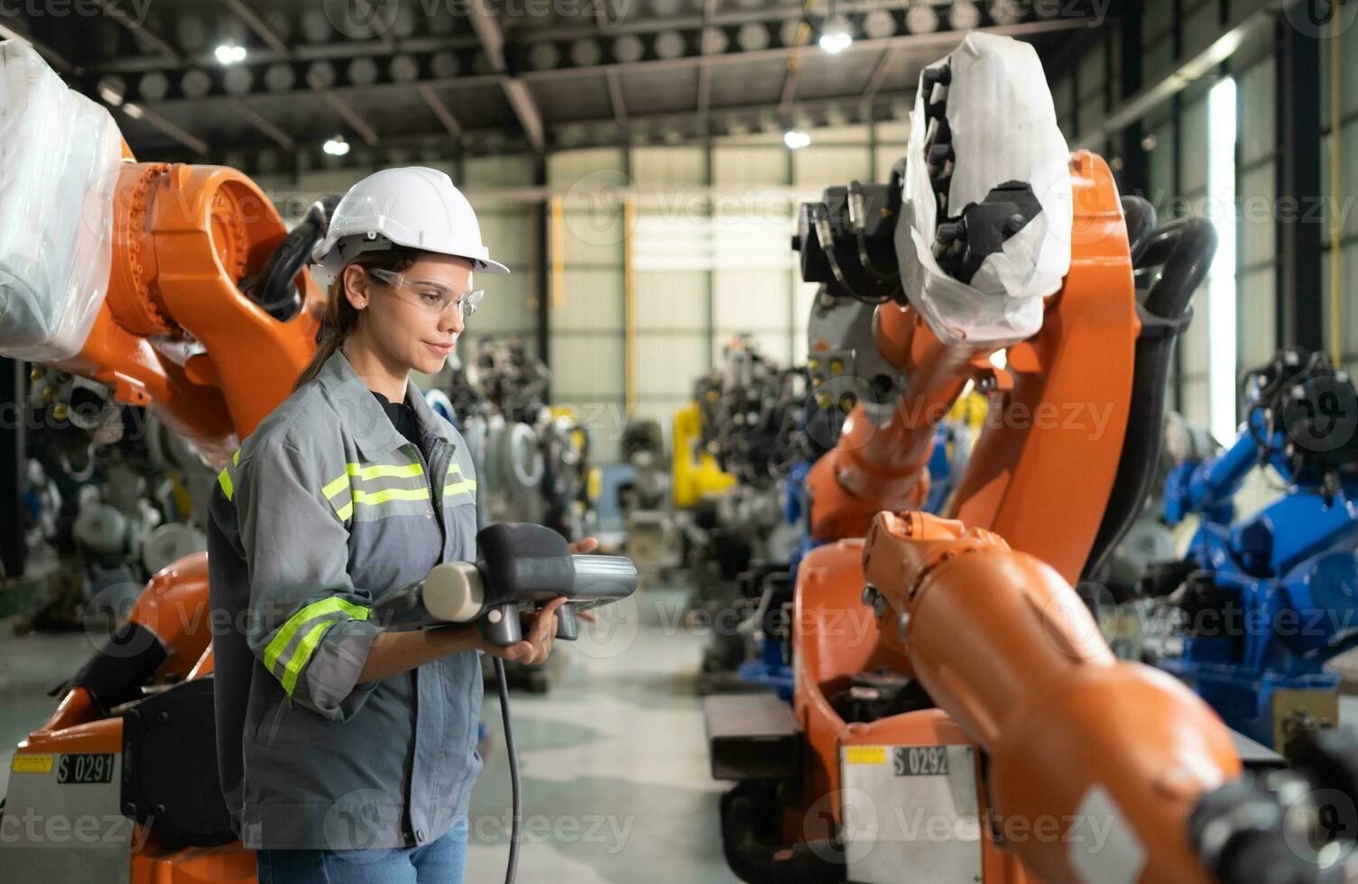 After installing a program on the robotic arm, a female engineer with a robotic arm controller performs a test run. photo