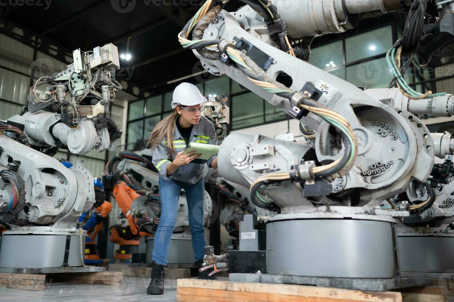 un hembra ingeniero comprobación documentado artículos después instalando un programa en un robótico brazo en un robótico almacén y prueba el operación foto