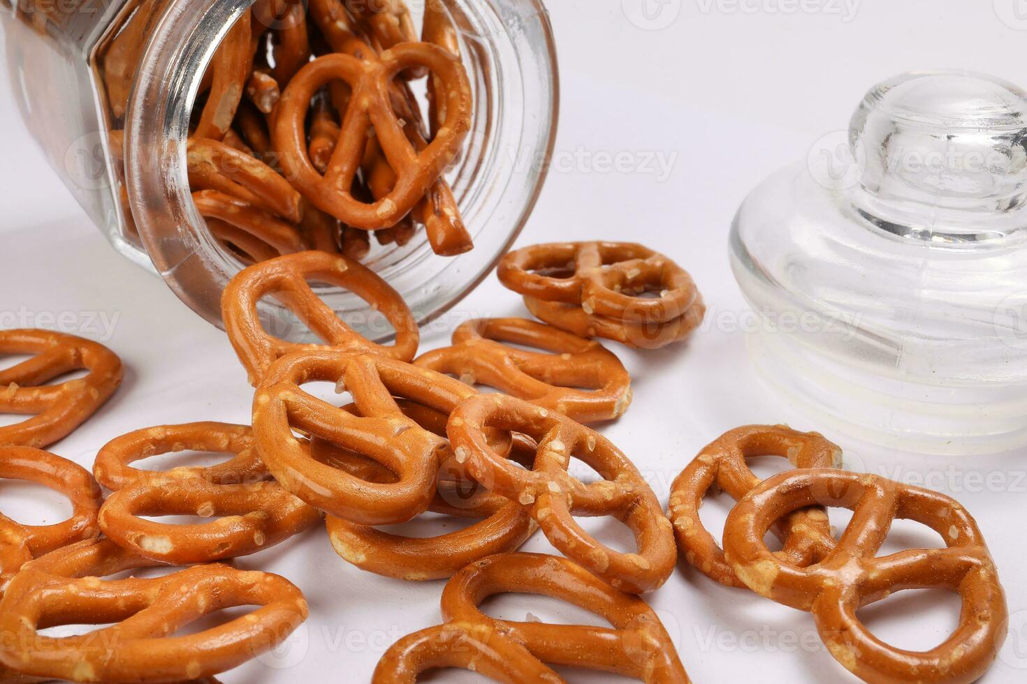 Pretzel cracker in a glass jar pouring dropping on white background photo