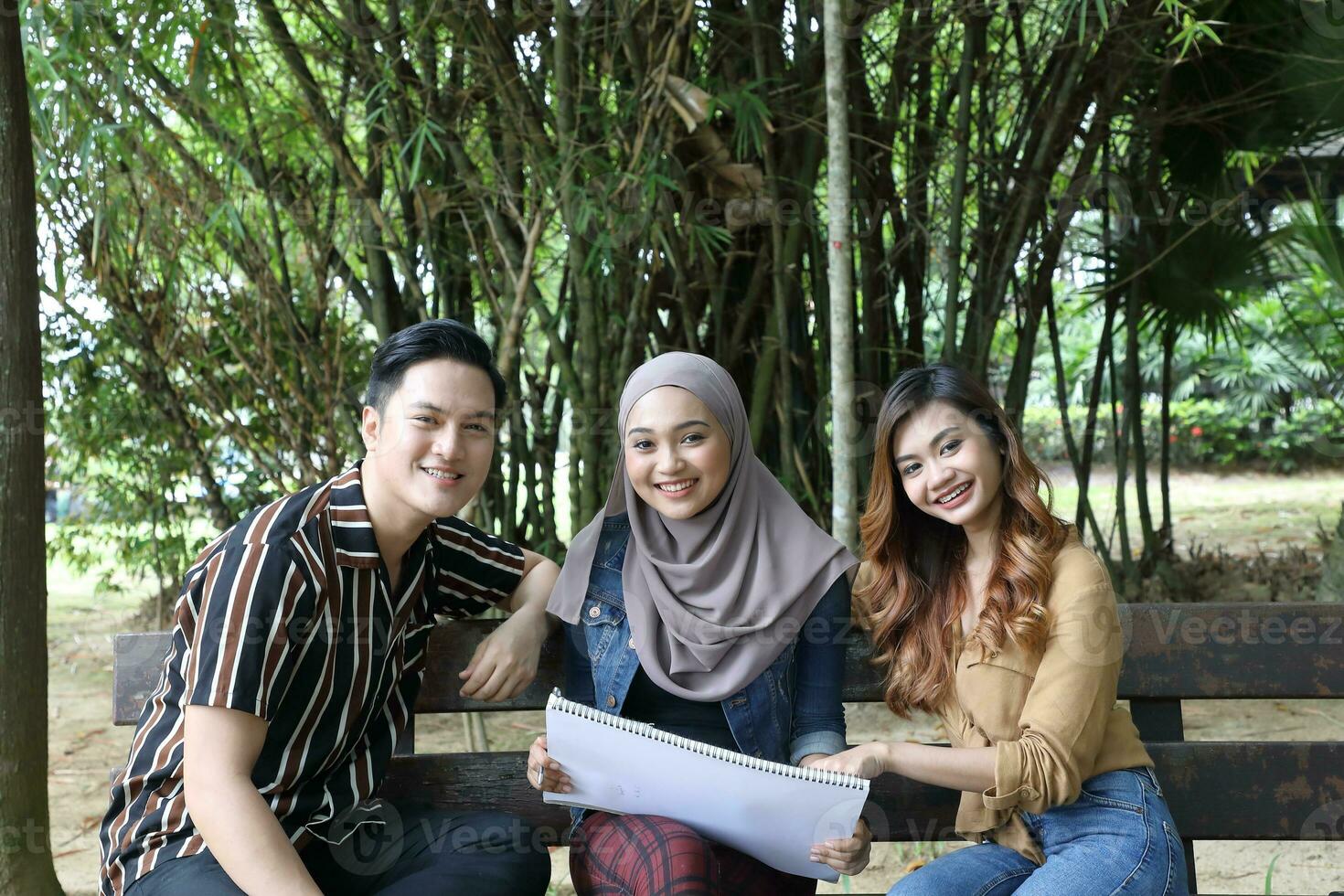 Young Asian Malay man woman outdoor green park walk talk discuss mingle photo