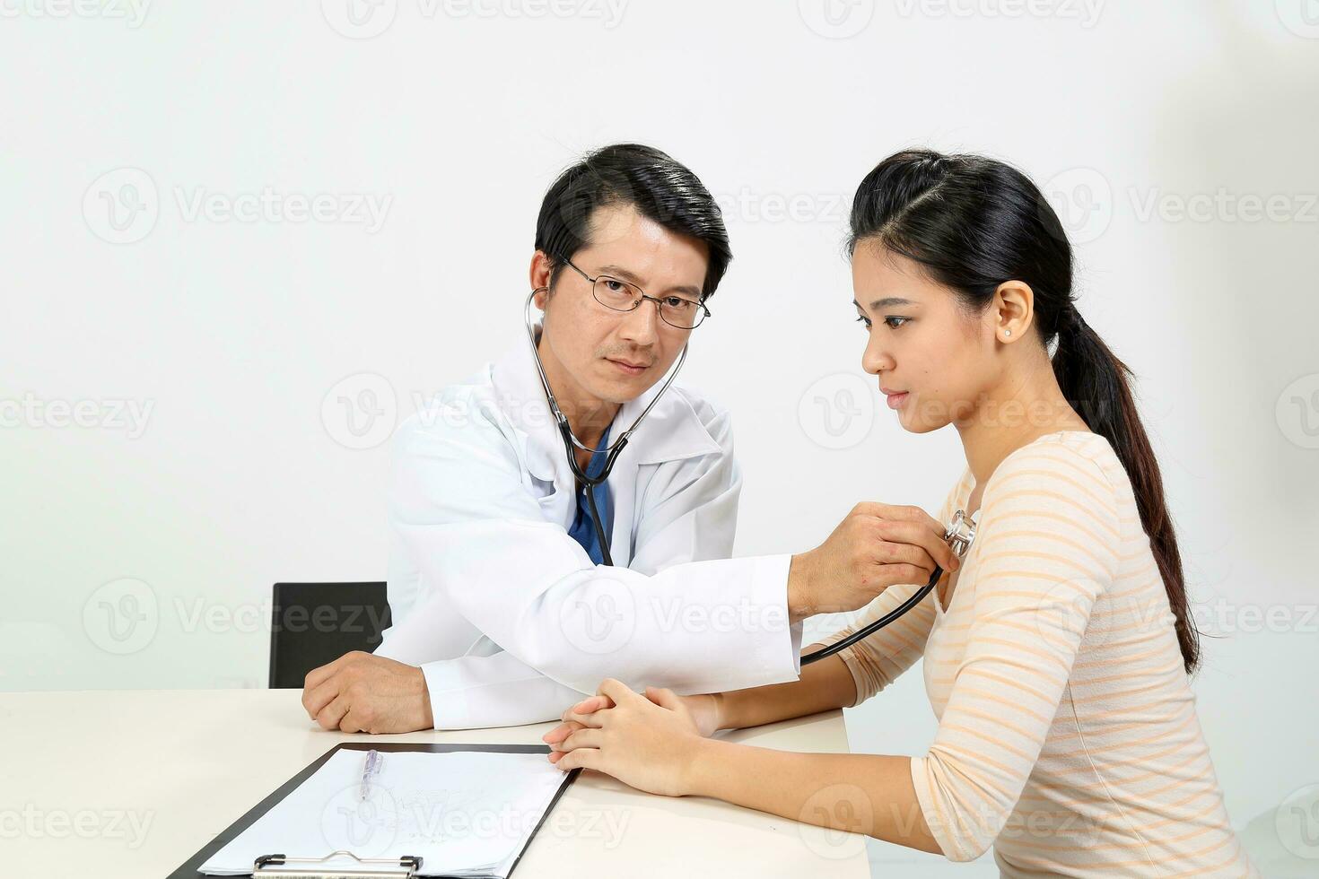 Young Asian male doctor wearing apron uniform stethoscope female patient talk discuss cheek photo