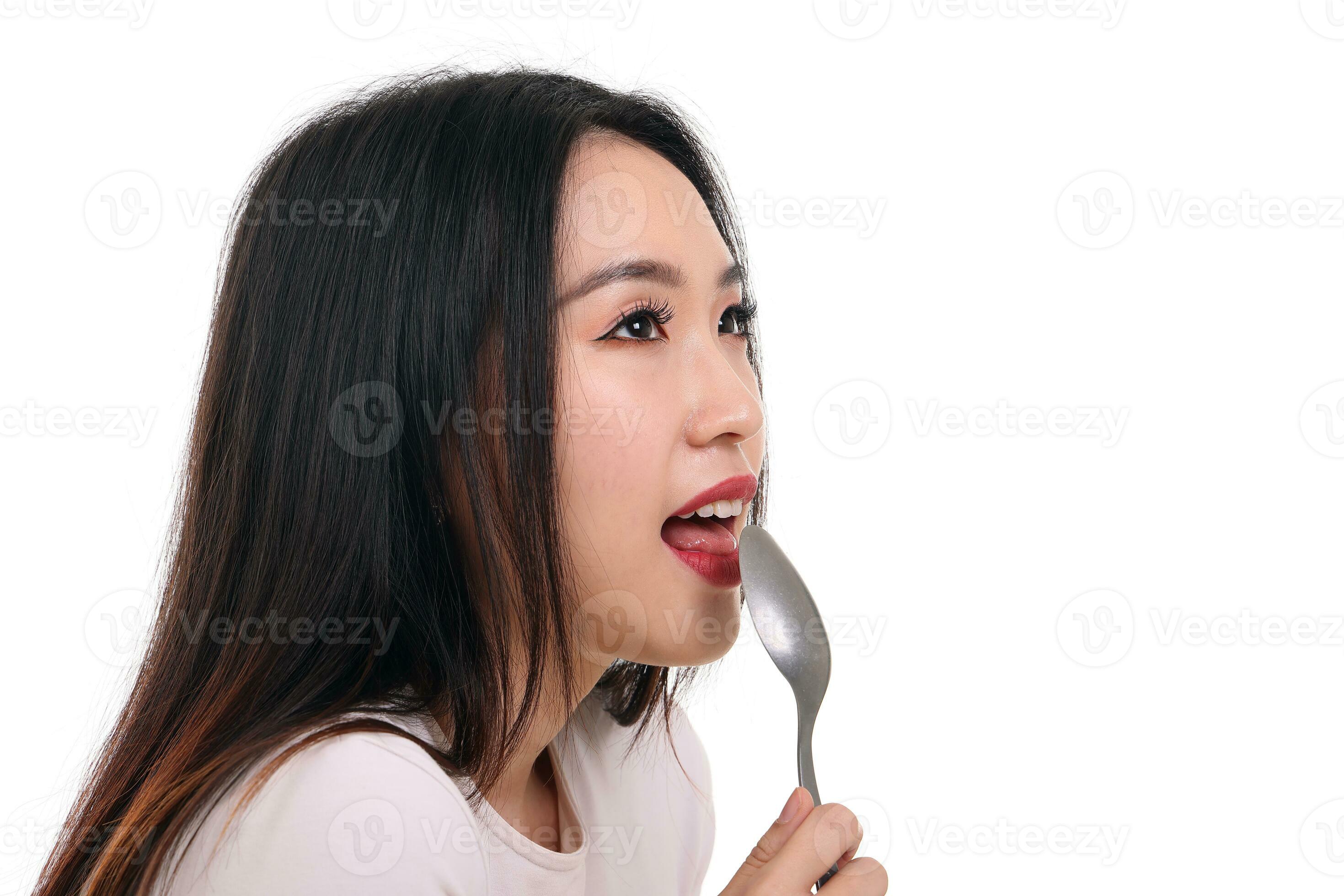Beautiful young south east Asian woman pretend acting posing holding empty spoon in hand on lips