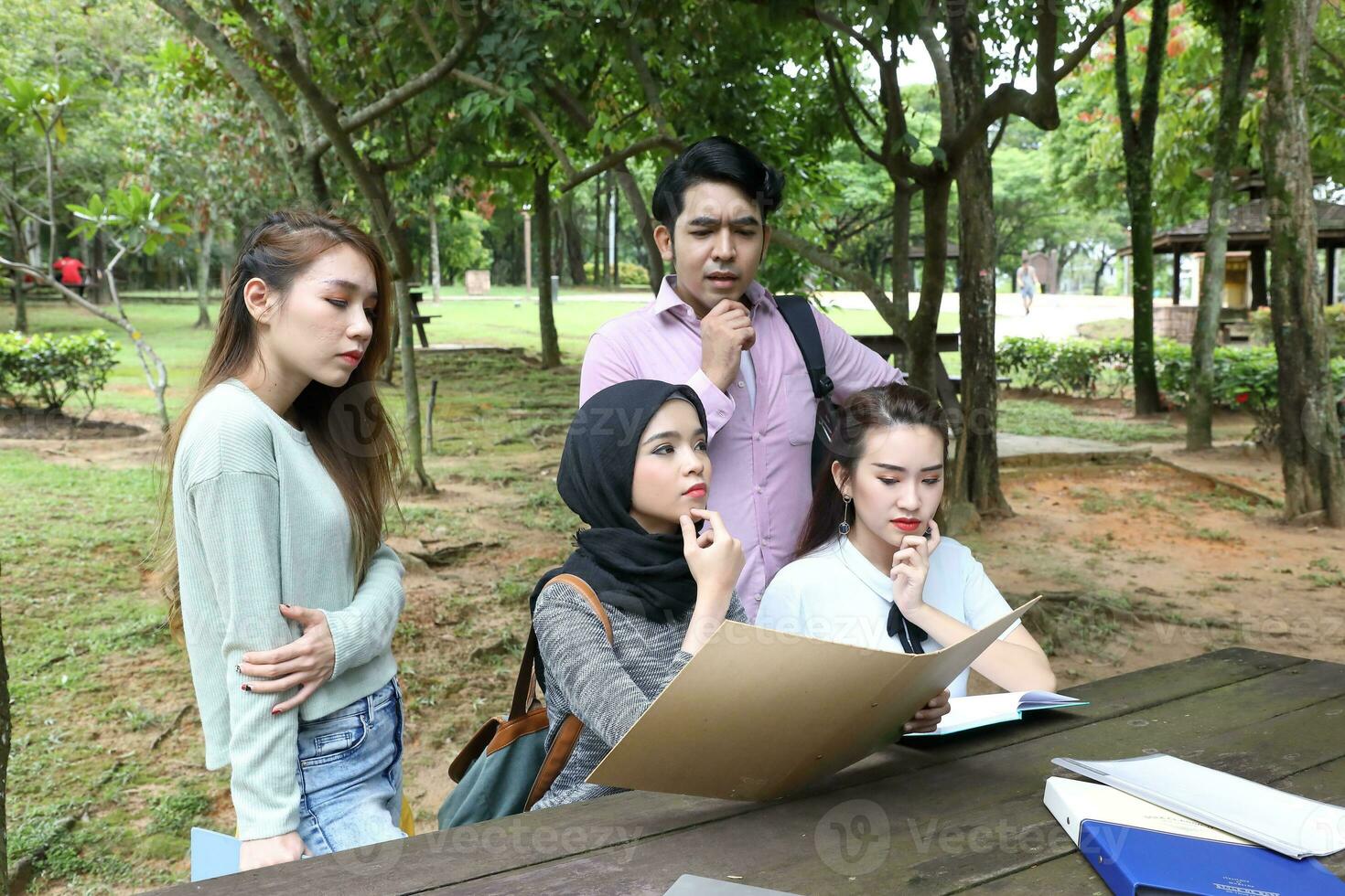 Young asian malay chinese man woman outdoor park  book file folder laptop computer phone sit stand study mingle photo