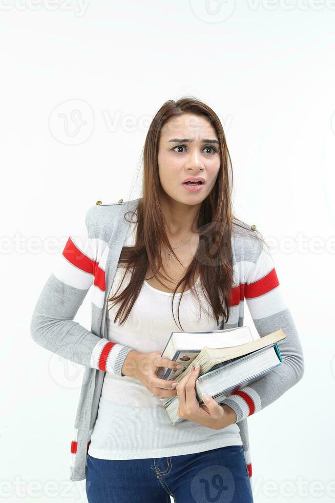 Yong Asian youth girl in casual dress carrying heavy book look at camera funny face expression difficult on white background photo